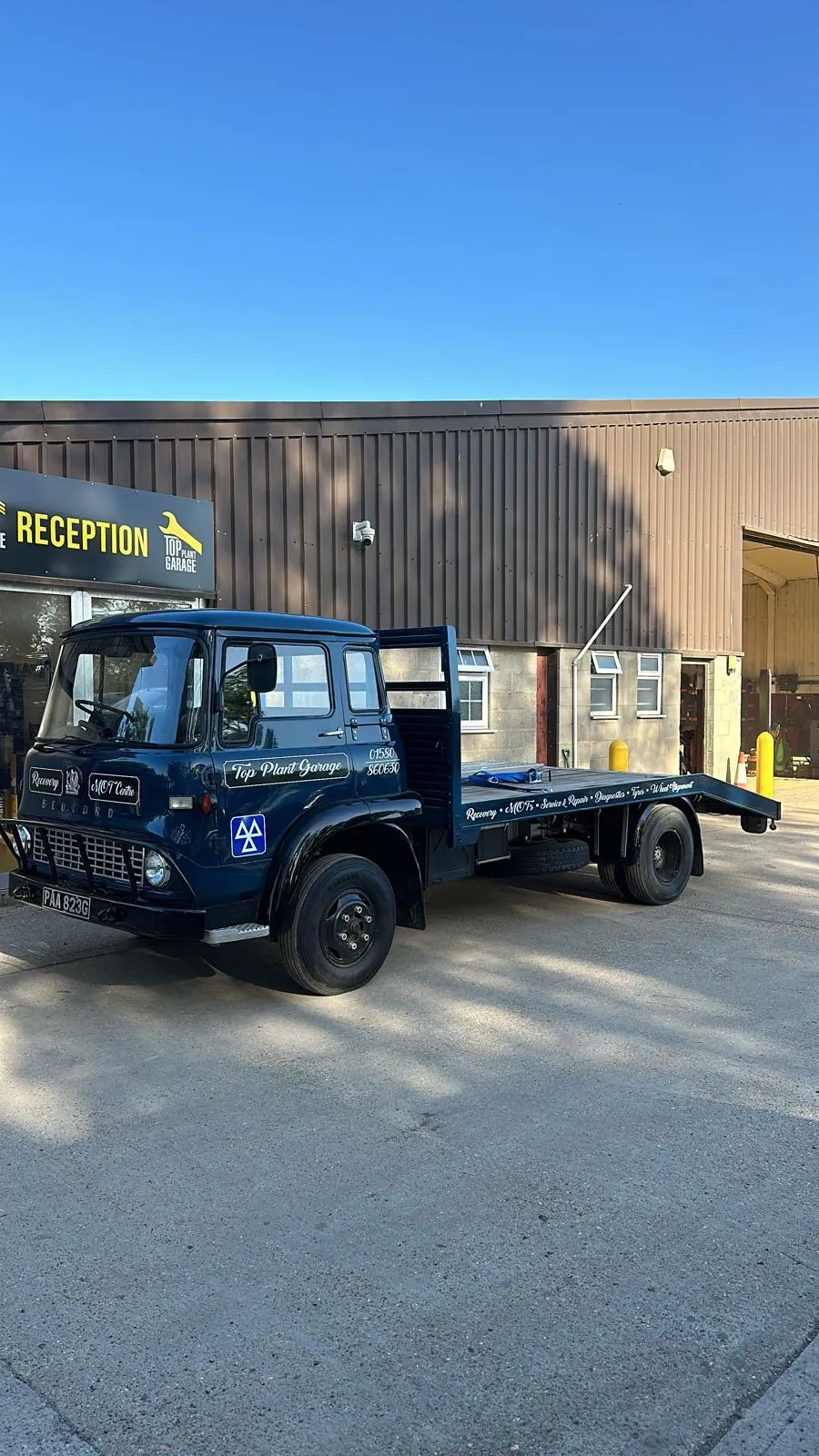 Top Plant Garage vintage blue recovery flatbed outside workshop