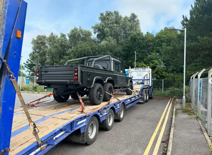 Land Rover-style off-road vehicle secured on a transport trailer